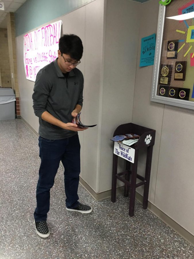 Adding magazines to the newsstand outside A201, senior Ryan Springs takes a quick look at the first ever Voice of the Wildkats magazine. Since going online, the newspaper staff plans on continuing print media in magazine form.   