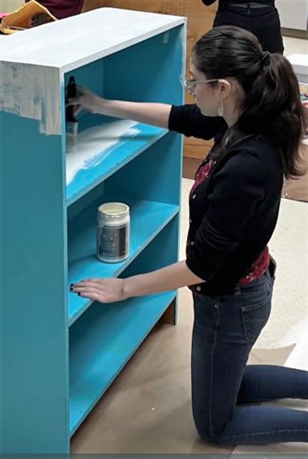 HELPING HANDS.  A member of Mrs. Hornes child development class helps paint a bookshelf at AR Turner. The group now goes to Roark Elementary School this semester to help with students at the school .