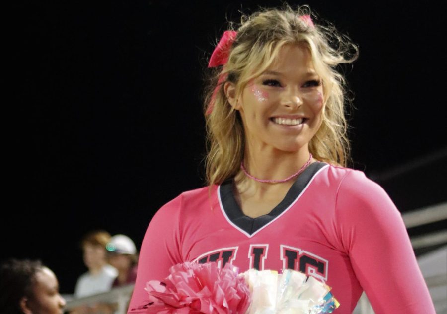 THURSDAY NIGHT PINK OUT. Showing support for breast cancer awareness, senior Faith Williamson wears pink glitter, a pink bow and cheers pink uniform. WIth the small number of home games, the Pink Out game was at an away game on a Thursday night. 