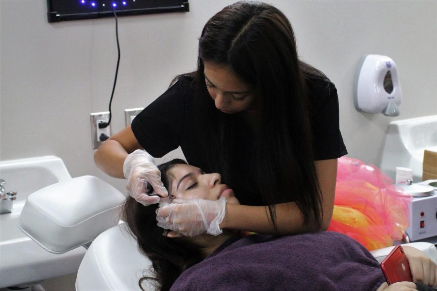 WAX ON, WAX OFF. Arching the eyebrows of junior Brizelda Vazquez, junior Emma Atkinson practices what she learned in class. 