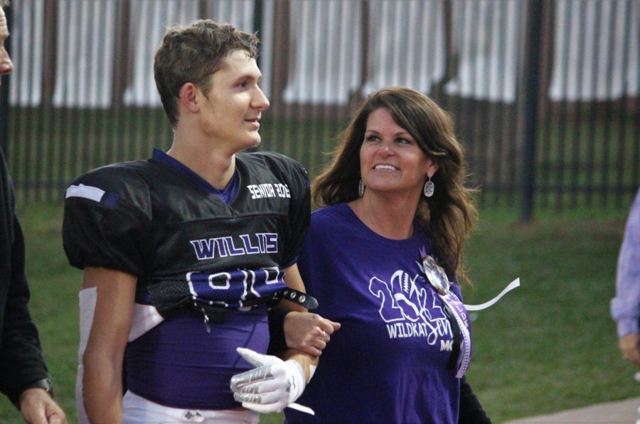 MAMAS PRIDE AND JOY. Before the game begins, senior Tanner Hayes is escorted by his mother Jennifer Walker down the track.