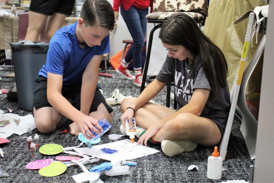 GLITTER MAKES EVERYTHING BETTER. Working on their door for Mrs. Ices room, freshman Cade Ford  and Kelsie Wyland add glue and glitter to the candy they are making. 