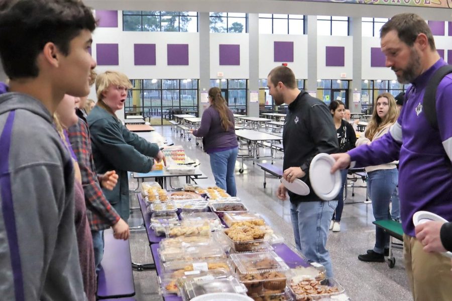 ALL FOR YOU. At the NHS breakfast for the staff, junior Reid Henderson encourages Coach Tim Knicky to grab breakfast before inservice on Jan. 4. 