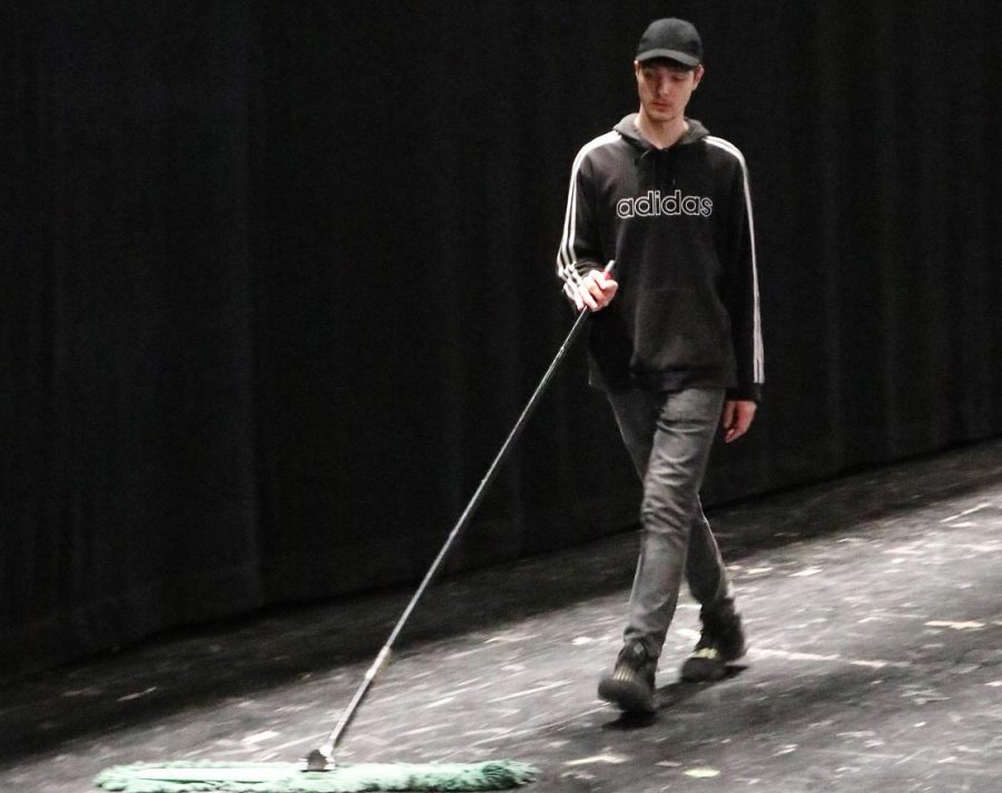PREPPING FOR THE LAST SHOW. Sweeping the confetti off the stage from the matinee performance, senior Timothy Brown gets ready for the last show. Brown served as the stage left manager for the show. 