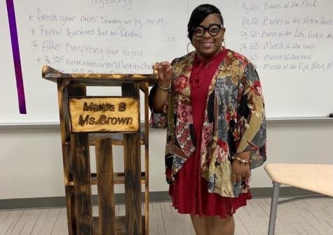 NEVER FORGOTTEN. Proud of her new podium, cosmetology teacher Callie Brown poses with the furniture bearing her name. Brown who fought a valiant fight against cancer, passed away in March.