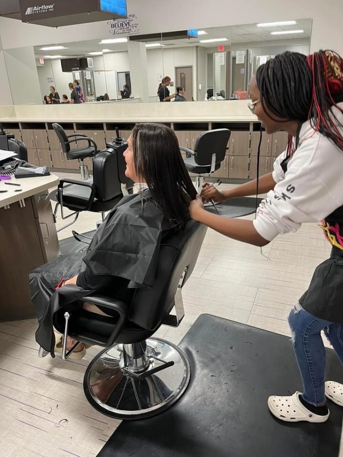 PRACTICING HER CRAFT. Working on getting the cut just right, junior Jemya Bonner 
cuts the hair of her client, Mrs. Roberts. 