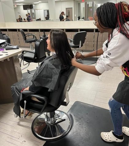 PRACTICING HER CRAFT. Working on getting the cut just right, junior Jemya Bonner 
cuts the hair of her client, Mrs. Roberts. 