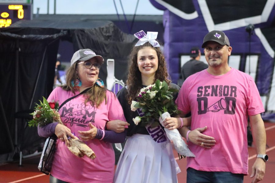 A HAPPY ENDING. At the last home game of football season, senior Katie Leggett smiles as she is escorted down the track by her parents. Leggett has been a part of the cheer team since her freshman year at Willis High School.