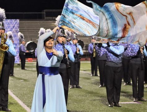 INTO THE BLUE. Performing in full uniform, sophomore Isabella Gallegos spins the flag as part of the bands show Into the Blue. 