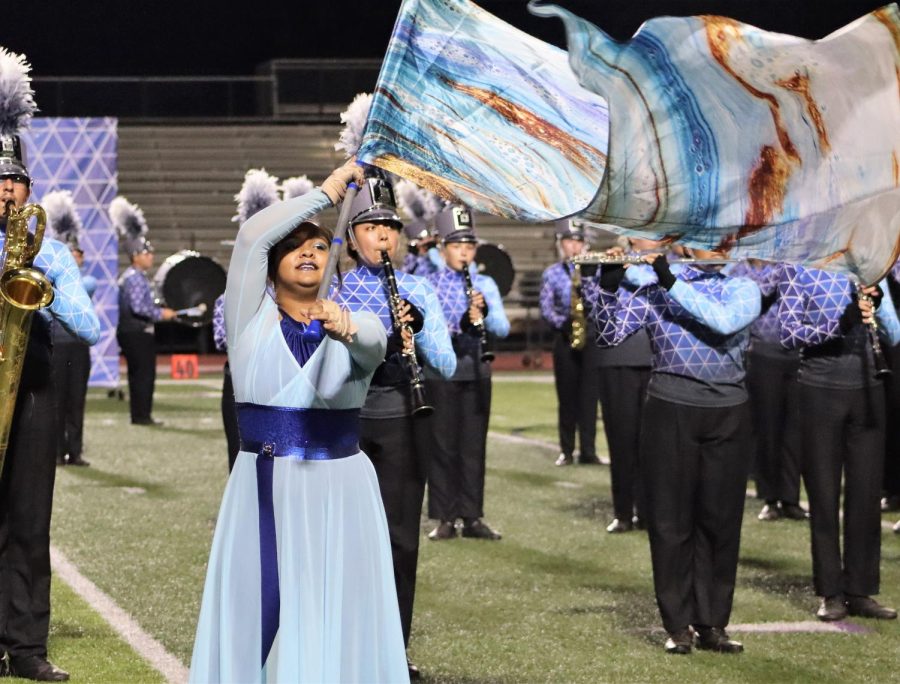 INTO+THE+BLUE.+Performing+in+full+uniform%2C+sophomore+Isabella+Gallegos+spins+the+flag+as+part+of+the+bands+show+Into+the+Blue.+