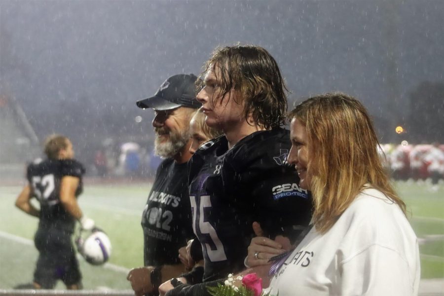SENIOR STORM. Before his last game at Yates Stadium, senior Ford Ivey is escorted by his dad, sister and mom while rain pours down on the crowd and the seniors who were being honored. The rain slowed during the game against The Woodlands Highlanders. photo by Hayleigh Brawley