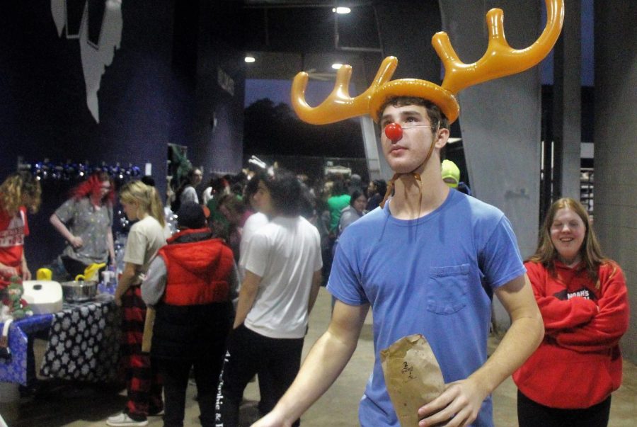 REINDEER GAMES. At Christmas in the Barn, junior Bradley Lottinger volunteers with DECA. As a game, children would throw rings at Lottingers reindeer horns. photo by Stone Chapman