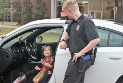 TO PROTECT AND SERVE. A visitor to Christmas in the Barn visits with senior Reid Henderson, a member of the law class. The group passed out cocoa, played games and allowed visitors to tour their car. 