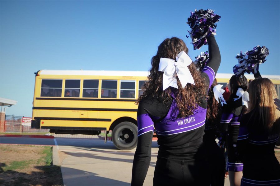 WILDKAT WAVES. Cheering as the bus leaves the parking lot, senior Katie Leggett and the other junior and seniors cheerleaders join the drumline, Sweethearts and other fans saying goodbye to the wrestling team. The team is competing at regionals this weekend in Allen.