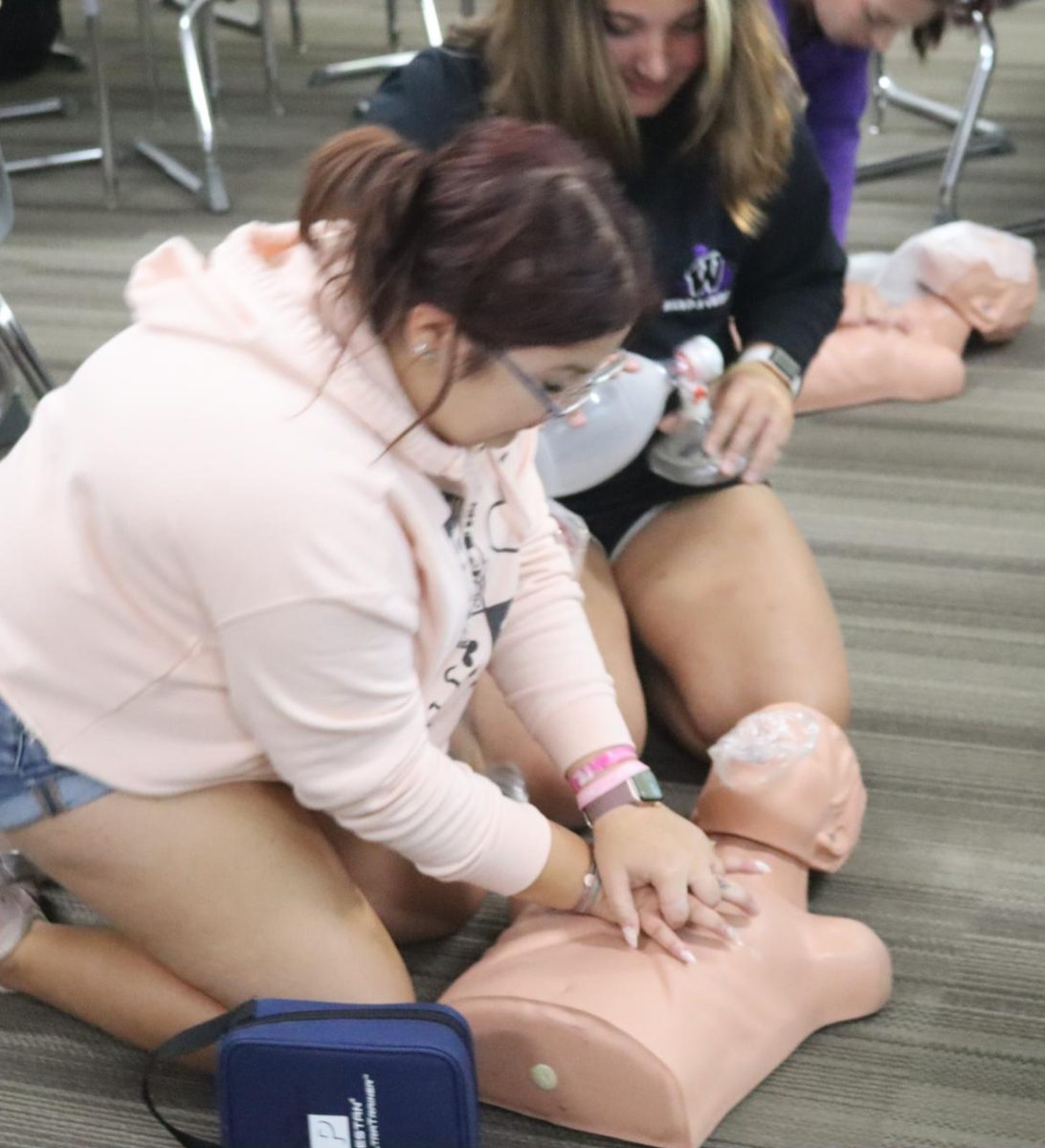 STAYING ALIVE. Seniors Sophie Hicks and Maddie Carroll practice giving CPR on a mannequin. Being CPR certified is one of the minimum requirements in order to succeed in the course.