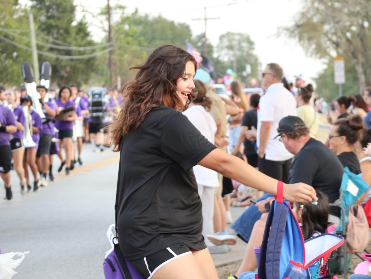 FAMILIAR FACES. Running to say hello to a friend, senior Nevaeh Scholwinski passes out candy to familiar faces at the end of the parade. 