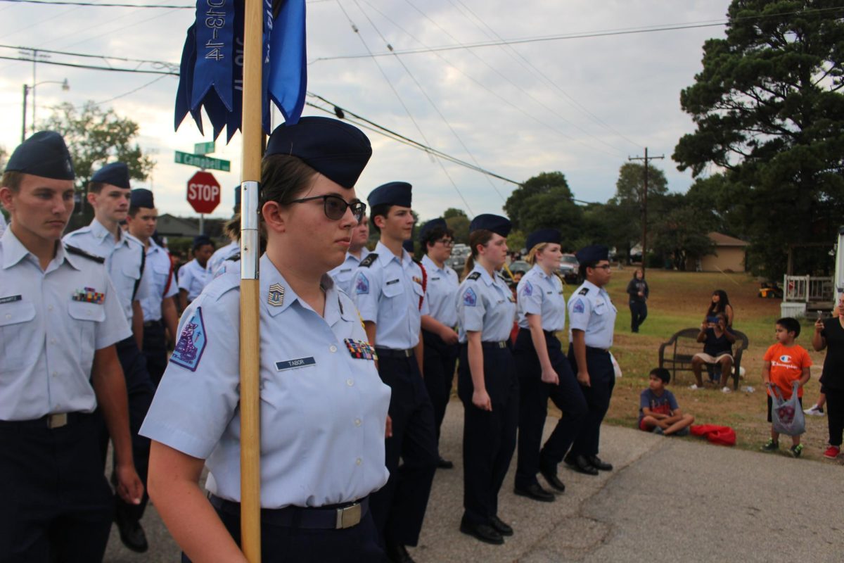 GUIDON. Cadets march at the homecoming parade guided by senior Tristen Tabor.