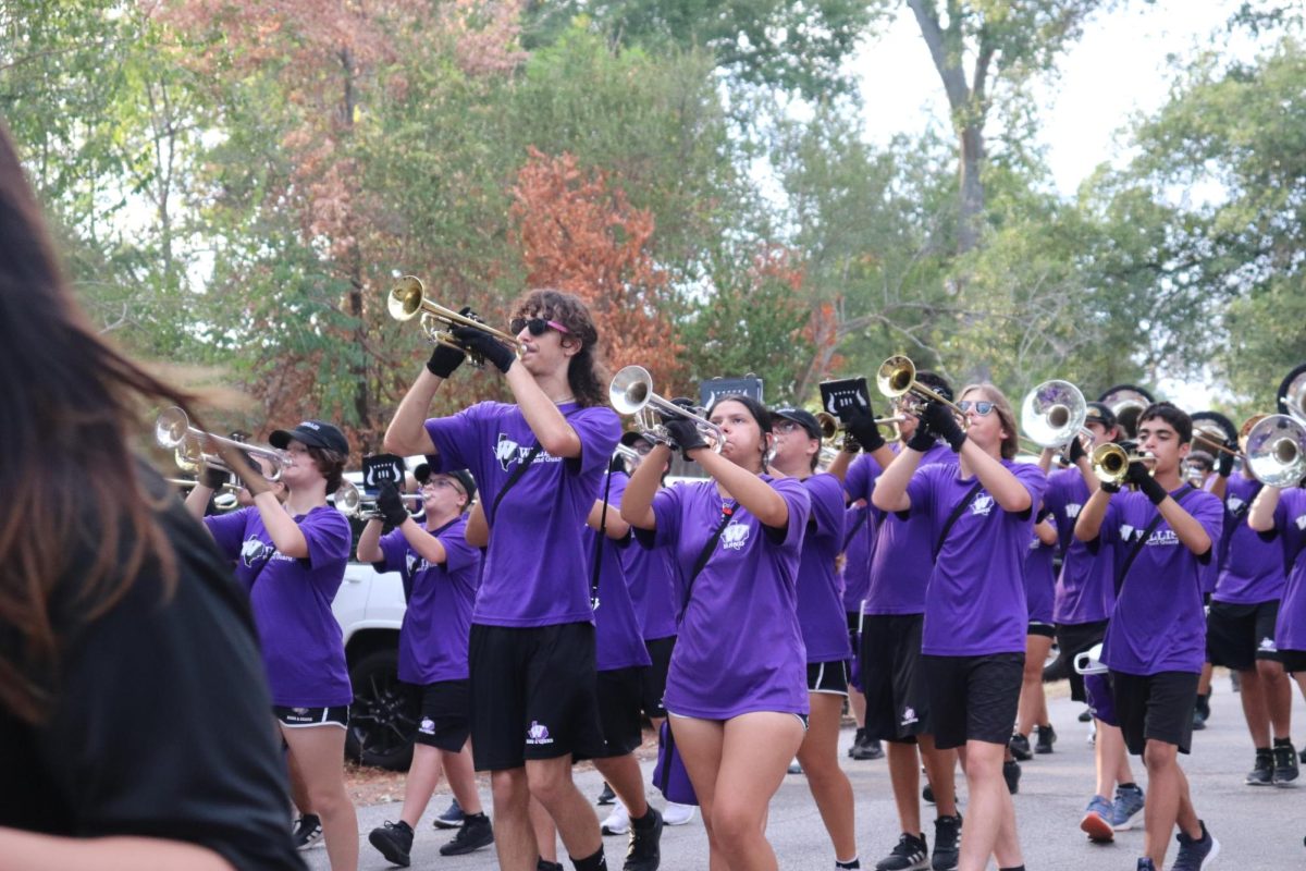 MARCHING MADNESS. Making their way around the parade route, junior Eli Maddox and senior Ally Henry play with the band. 