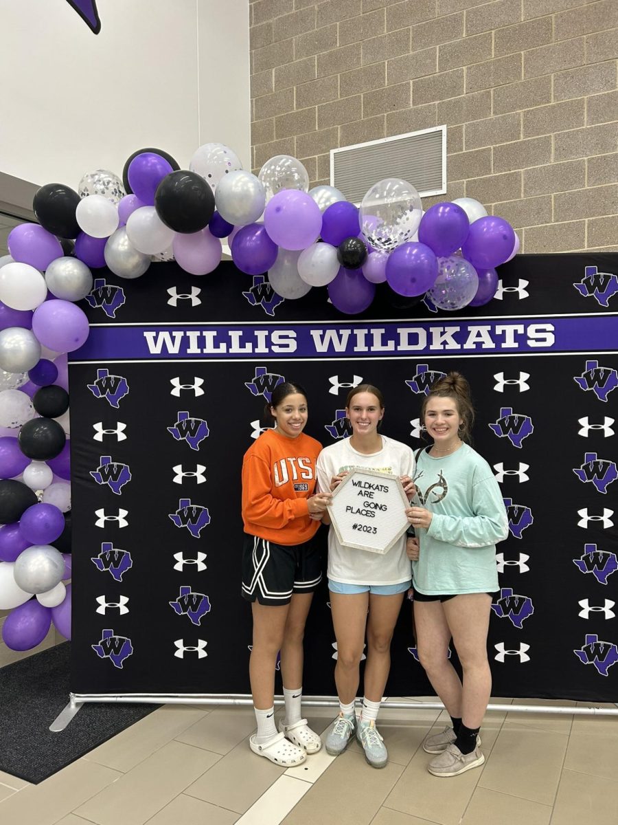 GOING PLACES. Sophomores Kamryn Davis, Amy Roberts and Rebecca Vaughn use the Wildkat backdrop to take a picture at College and Career Night. Forty four different colleges and programs came out to represent.