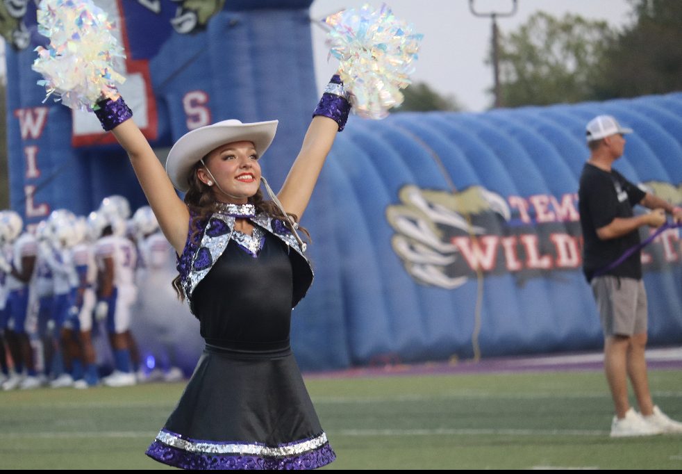 SWEETHEART SMILE. Shaking her poms while on the field, freshman Daisy Skelton smiles as she stands on the victory line.