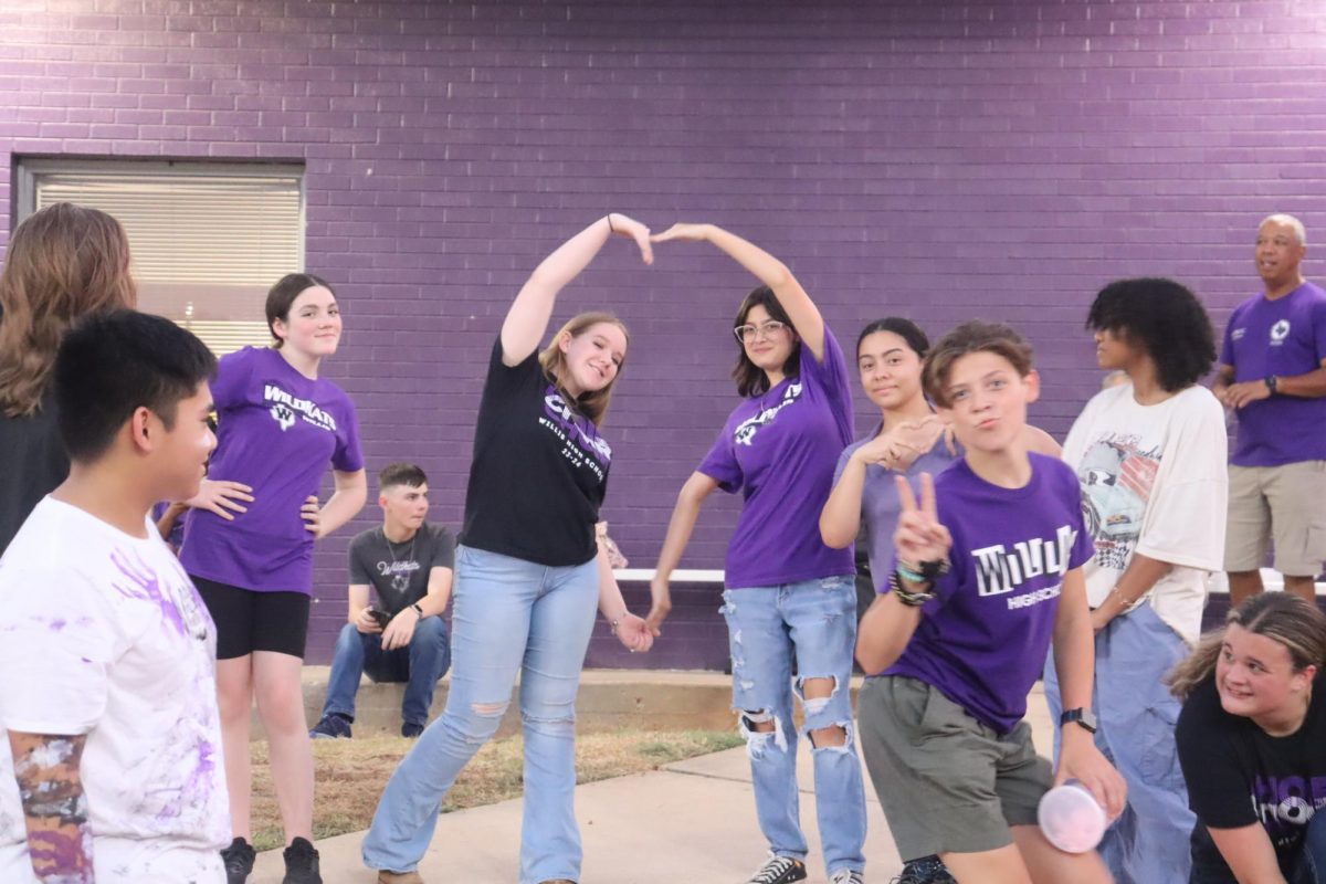 CLOWNING AROUND. Waiting to raise the flags freshman Tabitha Long and Alexia Recio form a heart with their hands to show their love for AFJROTC.