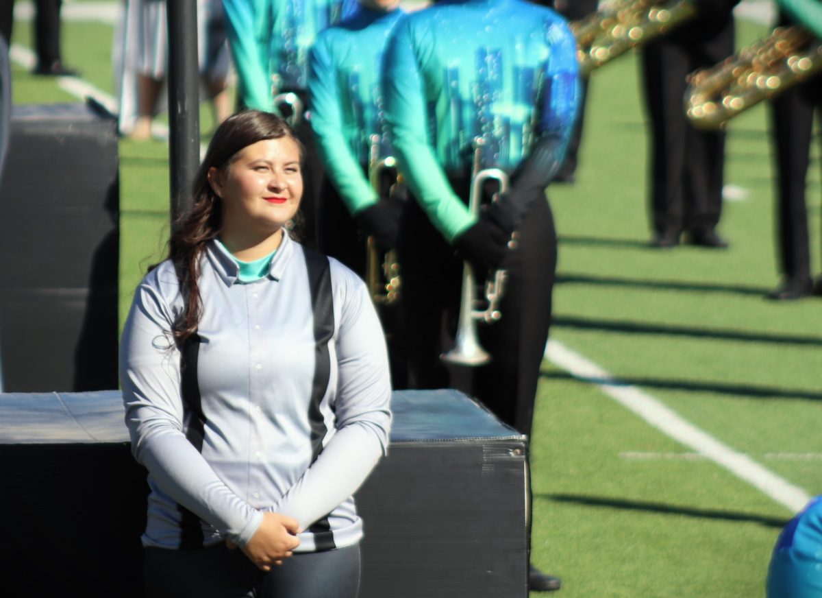 IN THE CITY. Waiting for the show to start, sophomore Chloe Roach, a member of the color guard, waits to entertain the crowd. 