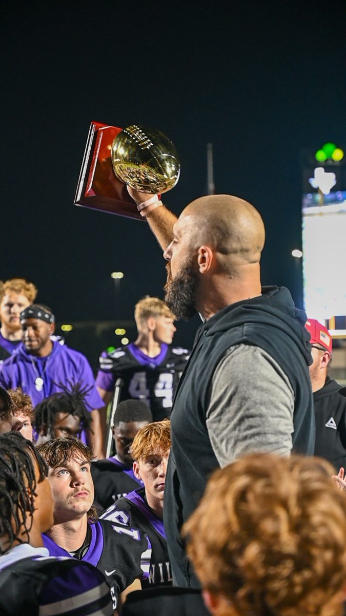 AREA+CHAMPS.+After+a+win+over+Tomball+Memorial%2C+coach+Trent+Miller+holds+the+area+trophy+high+in+his+after+game+talk+with+his+team.+The+WIldkats+will+face+Desoto+Friday+night+at+the+Alamodome+in+San+Antonio.