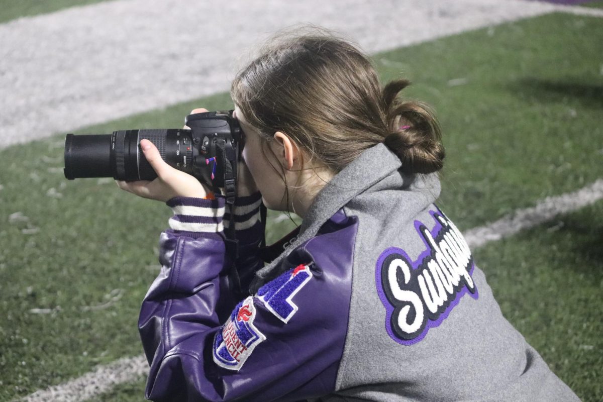 SIDELINE SNAPS. Focusing in on the action on the field, junior Danica Sundquist takes pictures for Wildkat Media.