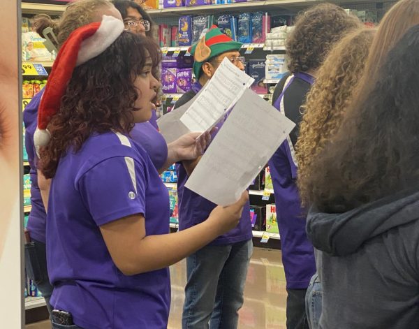CHIRSTMAS CAROLS. Singing Christmas music to get shoppers in the spirit, senior Gracie Saucedo and the Wildkat Choir perform at Krogers during the food drive.
