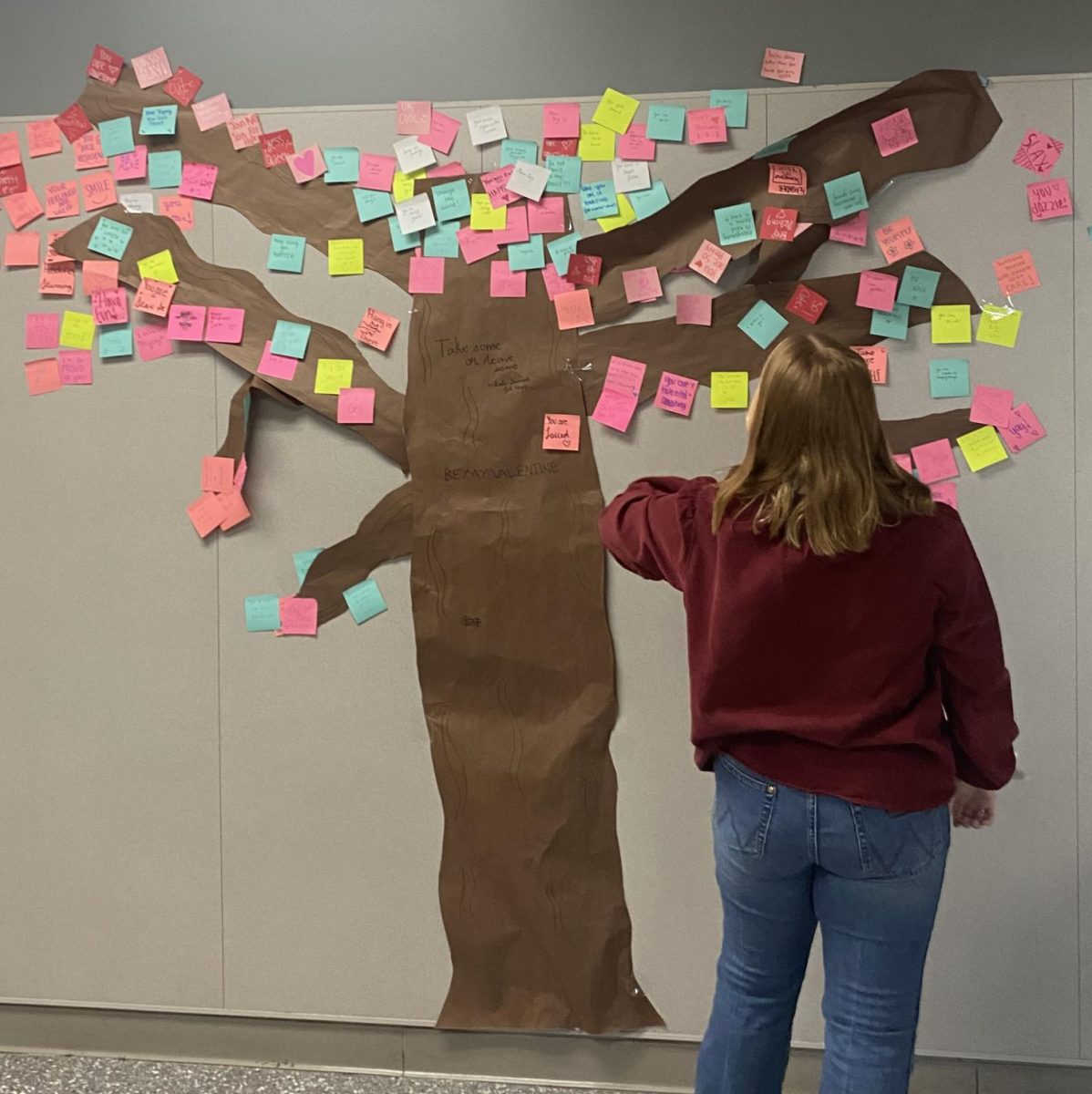 KINDNESS TREE. Placing a post-it on the tree, sophomore Morgan Smith adds a word of encouragement. 