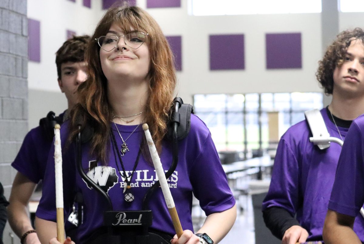 SETTING THE BEAT. During the Walk of Champions celebrating powerlifting, the Sweethearts and bowling, sophomore Charlotte McKinney plays with the drumline. The drumline leads the walkthrough parade through the school in honor of the teams headed to state and national competition. photo Ashley Briones