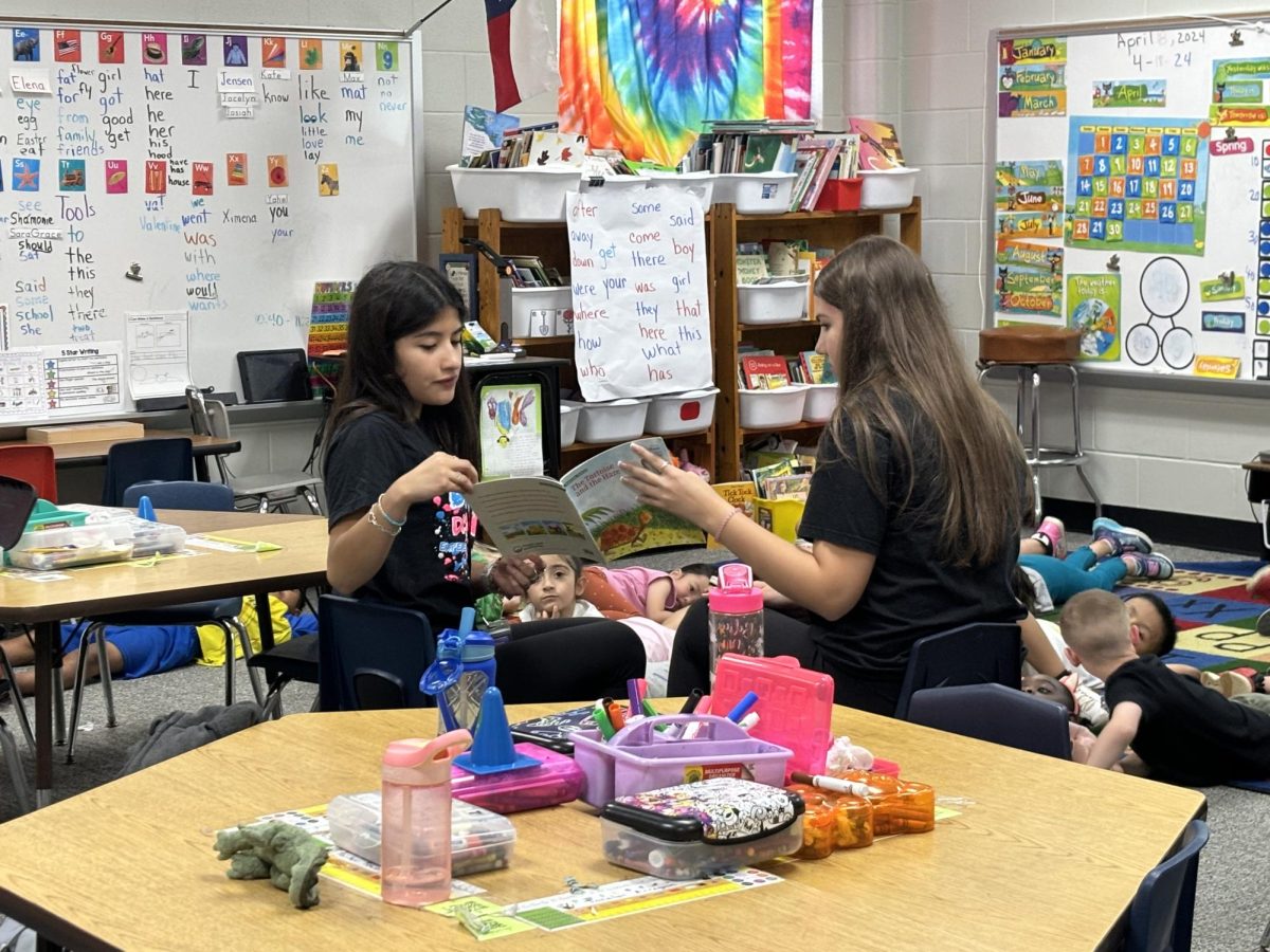 GIVING BACK. Reading to students at Turner Elementary, DECA students juniors Angela Garcia and Rebekah Steele give back to the community with their organization. 