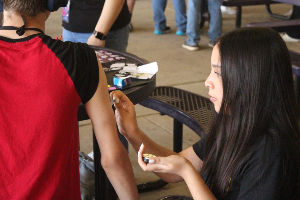 TATTOO ARTIST- Junior Victoria Perdomo paints students arm for Easter party. Their Easter activity was for the Special Education students where the event had vast activites such as bubble popping and bowling.