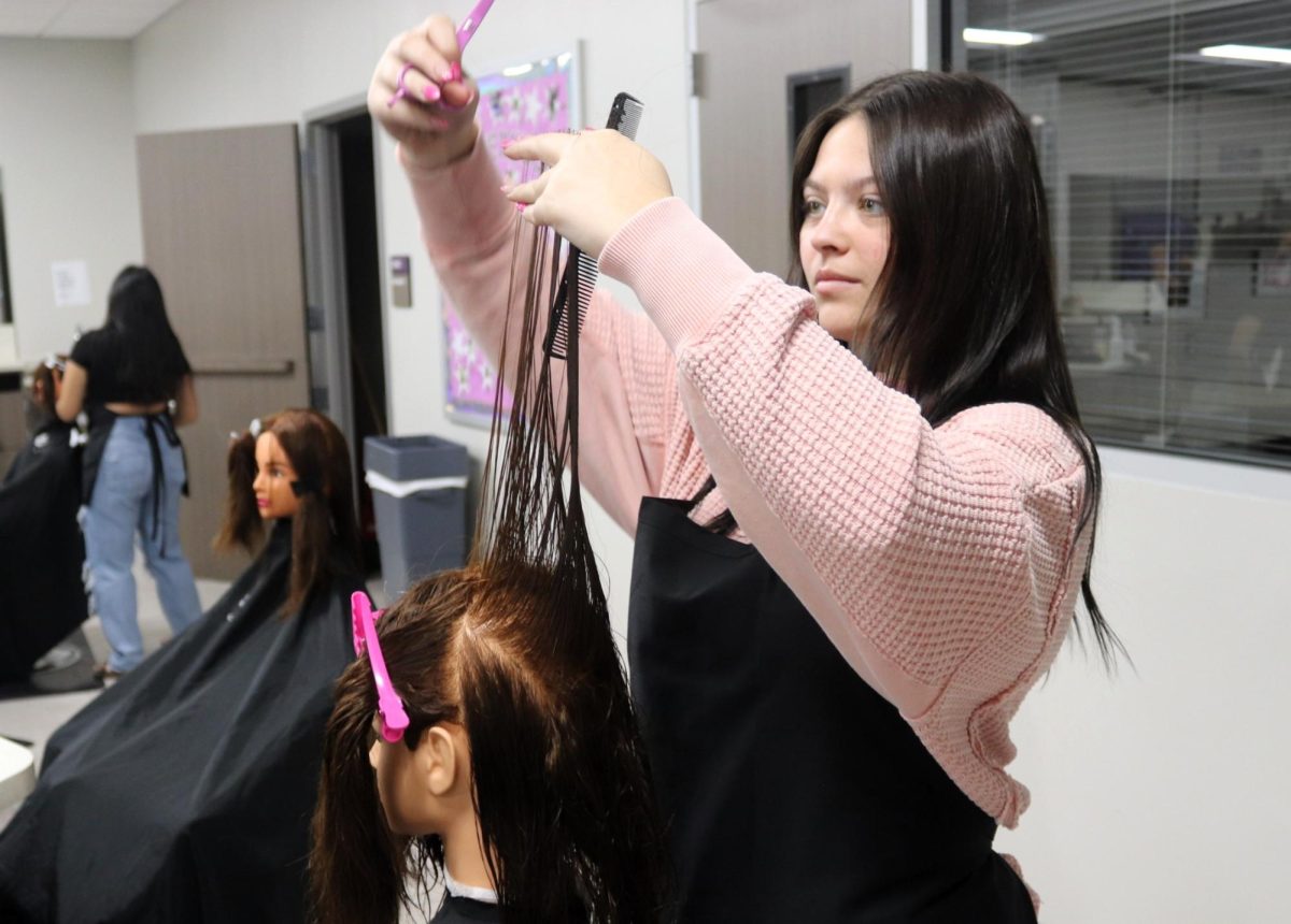 PRACTICE MAKES PERFECT. Working on her cosmo skills, senior Zoey Varner cuts a mannequin's hair during 3rd period cosmetology class. 