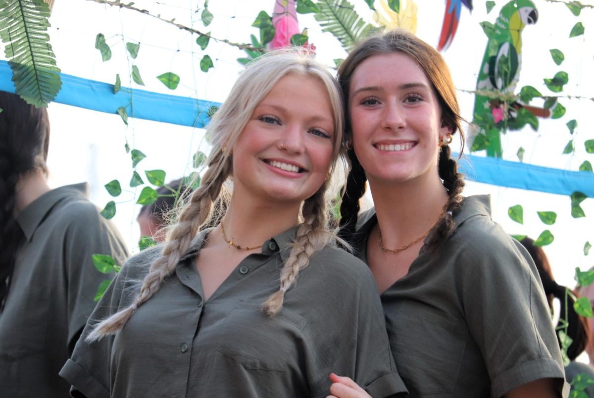 JUNGLE GAMES, Fresh from Jumanji, senior Brianna Hendrickson and sophomore Carli White ride on the float for volleyball. The JV and freshmen players walked along the float and passed out candy.