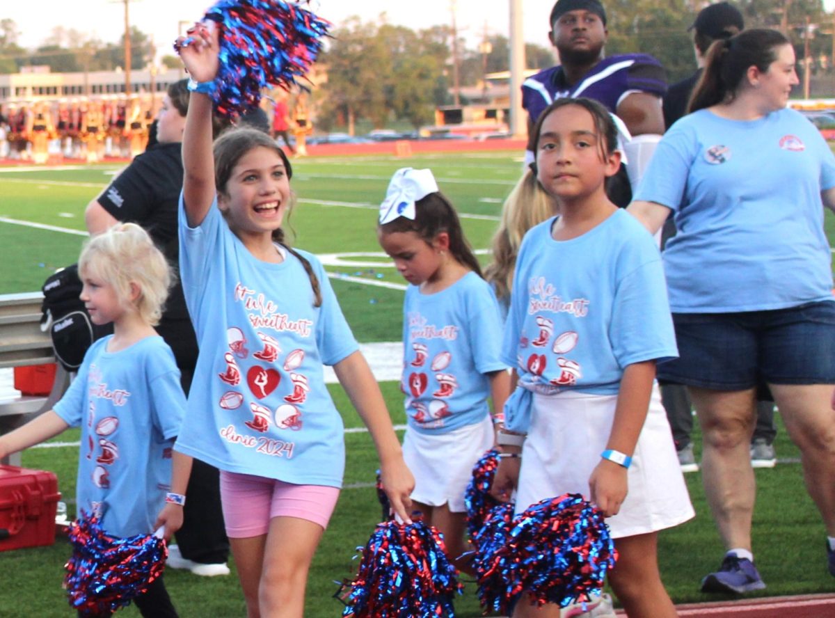 HIIIII. Waving at the community seated in the stands, a Future Sweetheart clinic participant walks off the field.