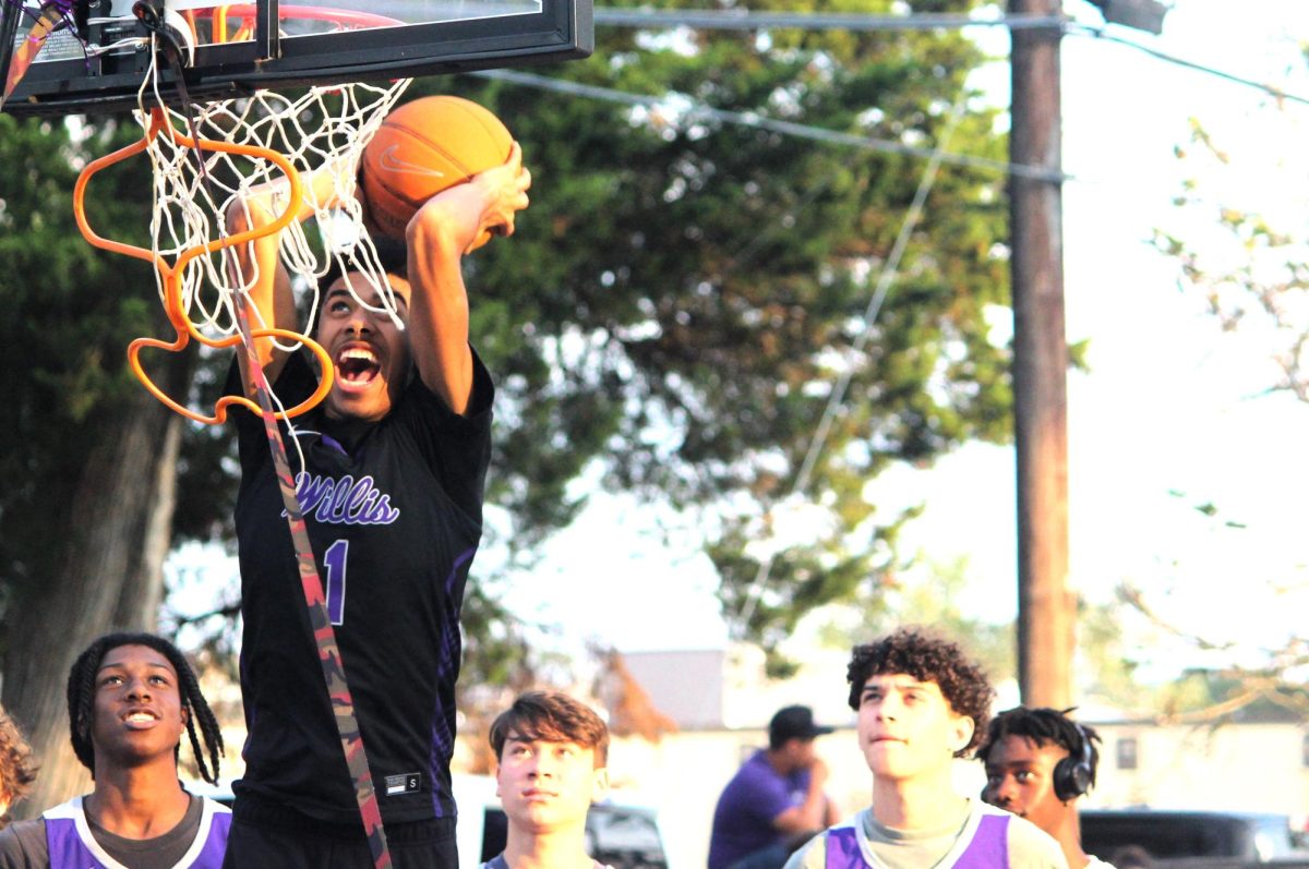 SLAM DUNK. Using the time in the parade to show off his basketball skills, junior SJ Young dunks on the basket that is part of the boys' basketball float. 