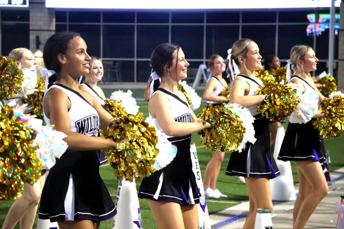 GOLDEN OPPORTUNITY. At the game against The Woodlands, sophomore Jaylynn Phipps, senior Gia Casso, junior Kyndall Schiffner and junior Courtney Pelton cheer with their gold poms. The cheer team incorporated the gold poms in honor of children with cancer.