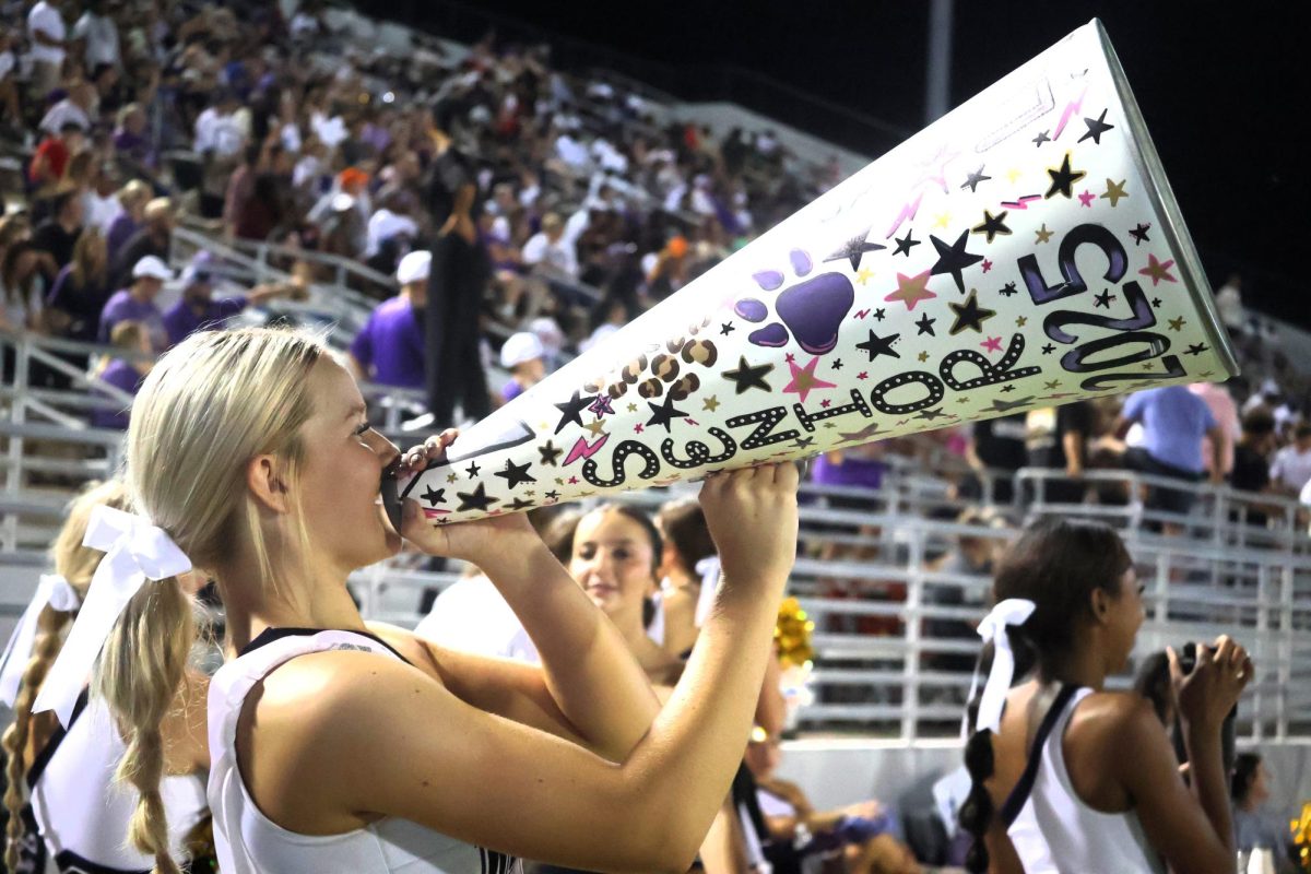 SENIOR SPIRIT The senior cheerleaders got to decorate their megaphones to show their school spirit. On the sidelines, senior Londyn Cox yells through her decorated megaphone to support the Kats. 