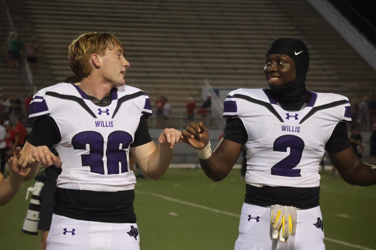 WILDKATS NEVER DIE. Before and after every football game, the Wildkat band plays school song. Locking pinkies, seniors Justin Willis and Kelan Harris sing along. 