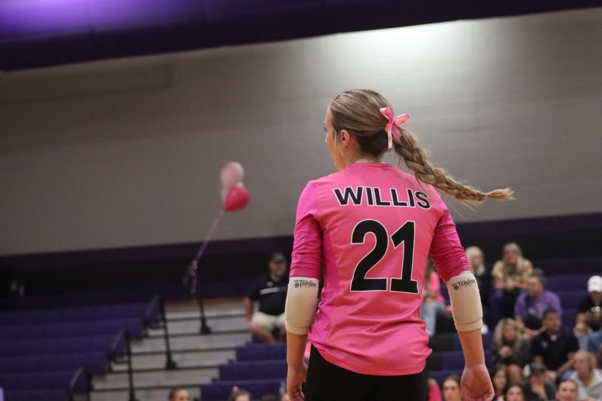 PRETTY IN PINK. Dressed in her pink jersey with a pink pow to match, junior Avery Wood plays in the match against The Woodlands on Friday, Oct. 4. The volleyball team hosted a pink out game in honor of breast cancer awareness. 