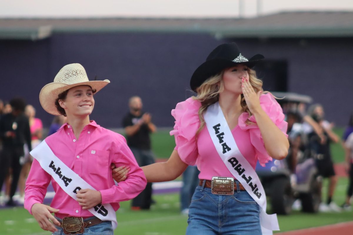 FFA REPS. Dressed with Western flair, seniors Mason Lightfoot and Denna Diggs walk the track as the FFA belle and beau before Fire Up the Kats.