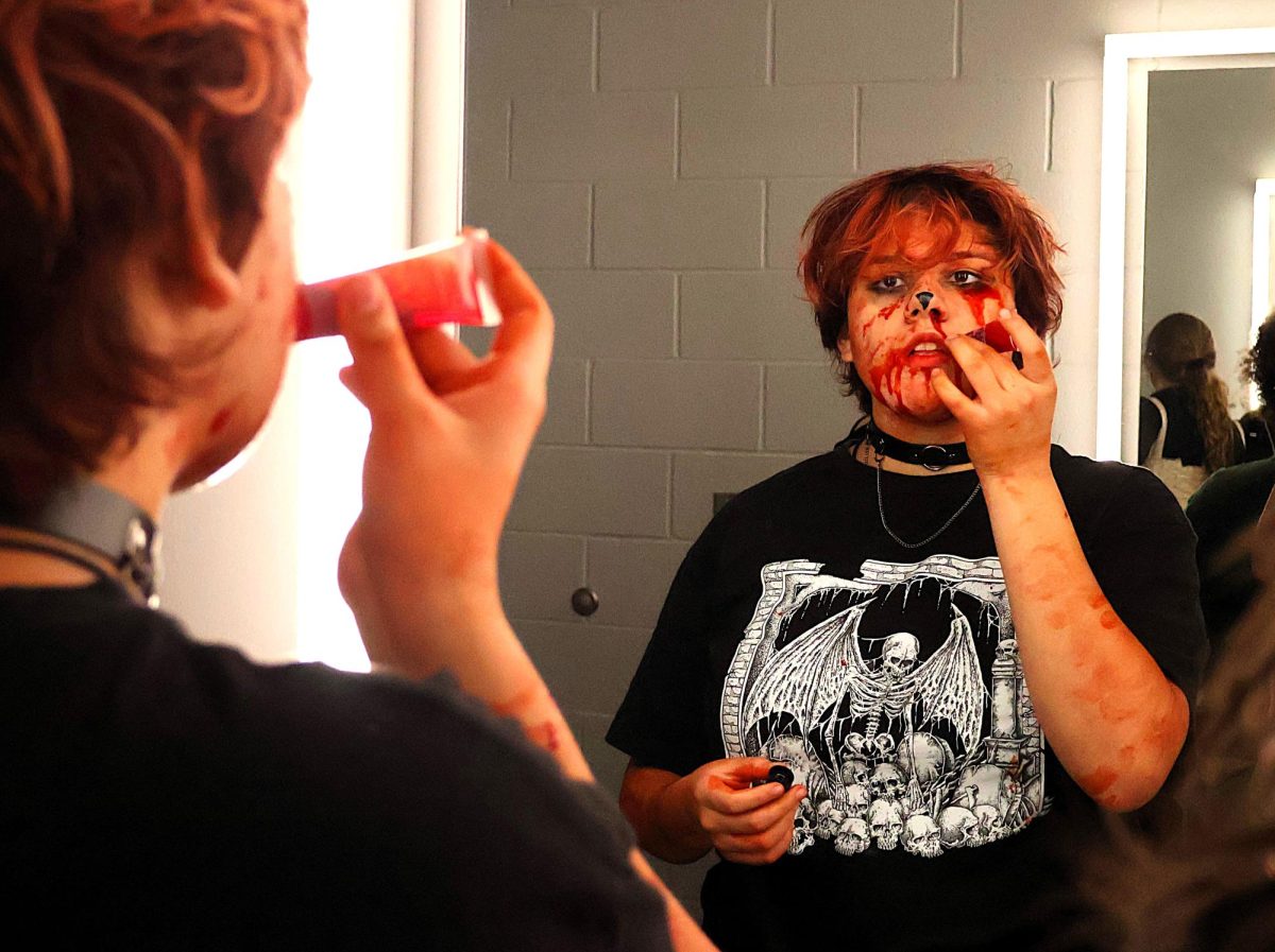 MACABRE MAKEUP.  Making her face extra scary for the haunted house, freshman Natalie Snoe applies fake blood to her makeup before the annual event. The drama department held the event on Wednesday night in the PAC. 