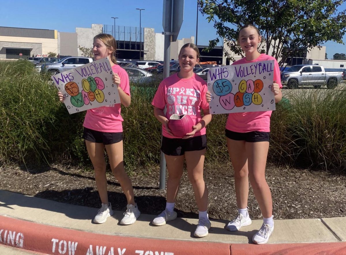 AT THE CARWASH. Advertising the carwash in the HEB parking lot, freshmen Finley McDonald, Bailey Allen and Kaylah Crabdree work at the volleyball carwash. The event raised money the team donated to charity. 