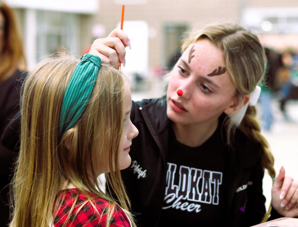 SANTA'S HELPER. At Christmas in the Barn, freshman Ryleigh Lewis paints faces. The cheerleaders joined clubs and classes from CTE for the annual event for elementary-aged children in Willis. photo by Maria Spencer