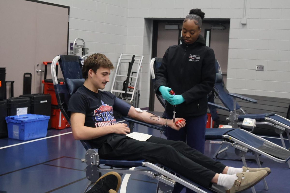 SAVING LIVES. While squeezing a stress ball, junior Aaron Barker sits down and gets ready to donate blood. On December 2nd,  the school set up a blood drive where the community can go donate. 