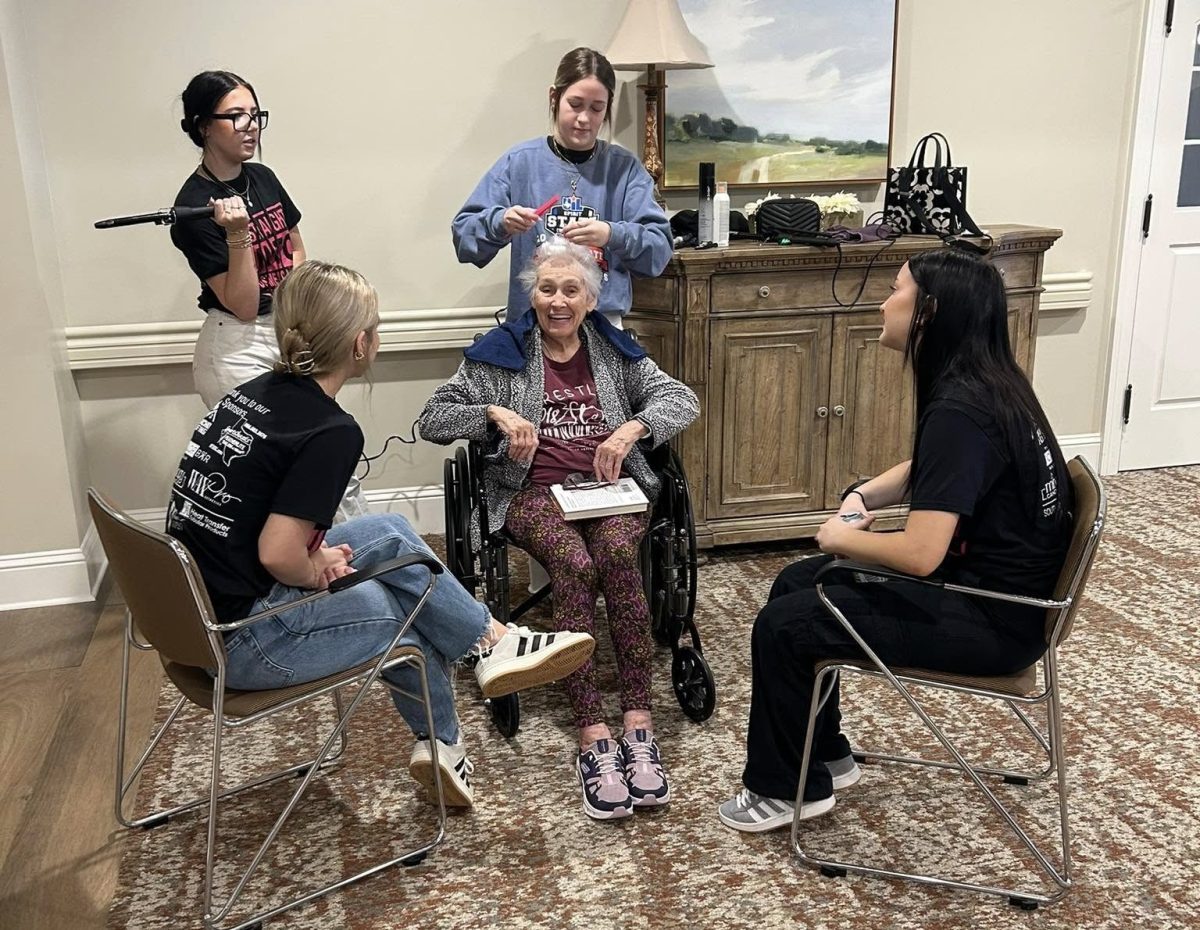 HAIR HAPPINESS. Surrounding a senior, juniors Kyndall Schniffner and Sadie Smith use teamwork to do hair as other cosmetology students socialize. The cosmetology group of students and faculty pampered residents at the Worthington Manor In Conroe.