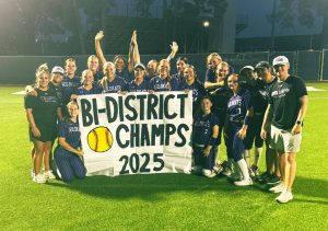 BI-DISTRICT CHAMPS. After the first round of playoffs, the softball team poses with a sign. After a strong victory against the Eisenhower Eagle's, the team advances to the next round of play offs. 