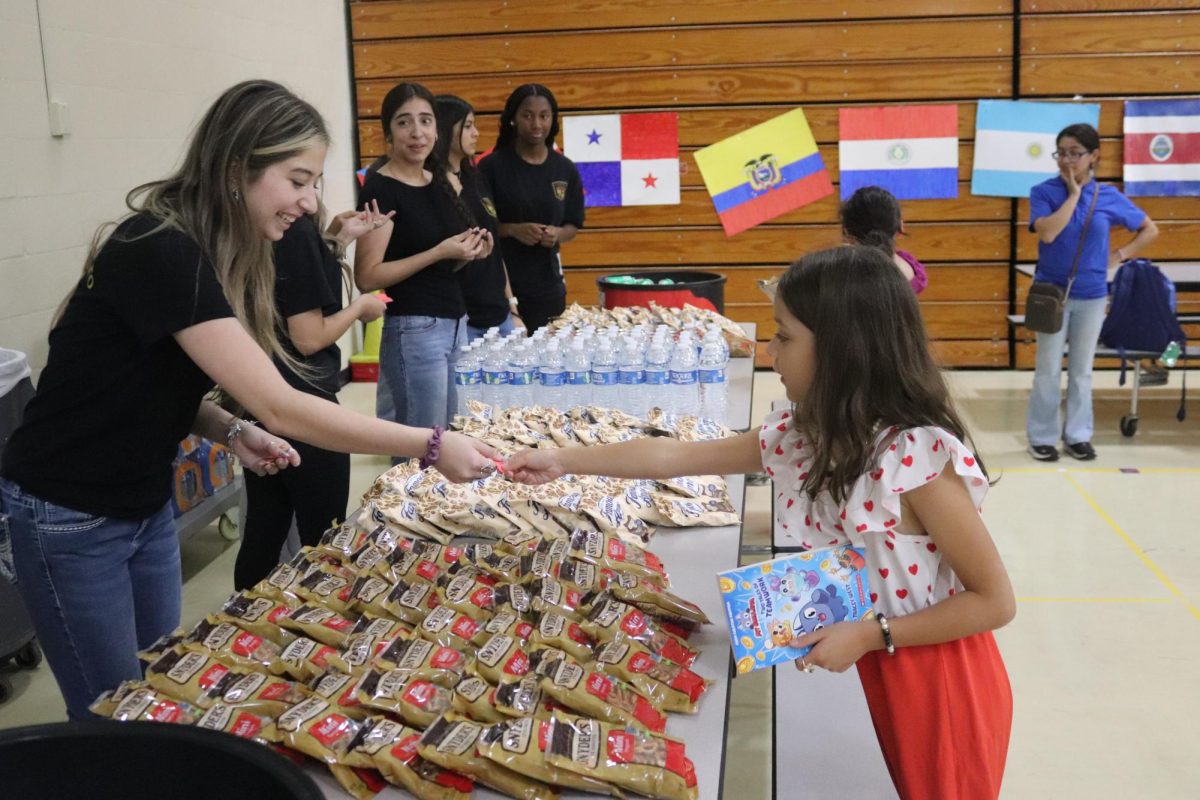  TICKETS PLEASE. Spanish National Honors Society president senior Victoria Medina helps C.C. Hardy student get her fill of cookies. Upon entry to C.C. Hardy's Fiesta Night, students and their families are each given a ticket for a free snack and drink run by the Spanish National Honors Society at Willis High School.