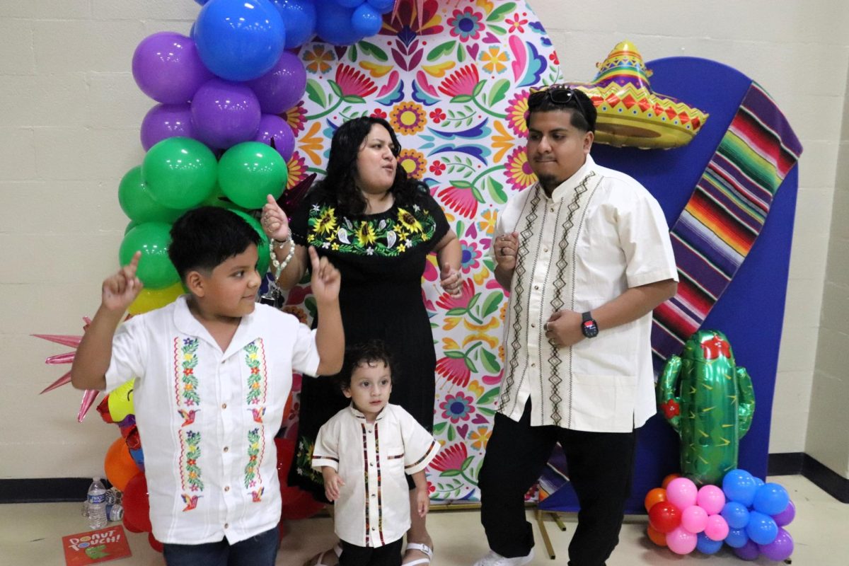 PHOTOS AND FUN. Unable to resist La Chona, C.C. Hardy student Zeke Rosales with his little brother Alec, mom Eiri, and dad Benji, take a quick dance break mid photo at the photo booth. Many families took the time on September 18th to make their way to Fiesta Night at C.C. Hardy Elementary.
